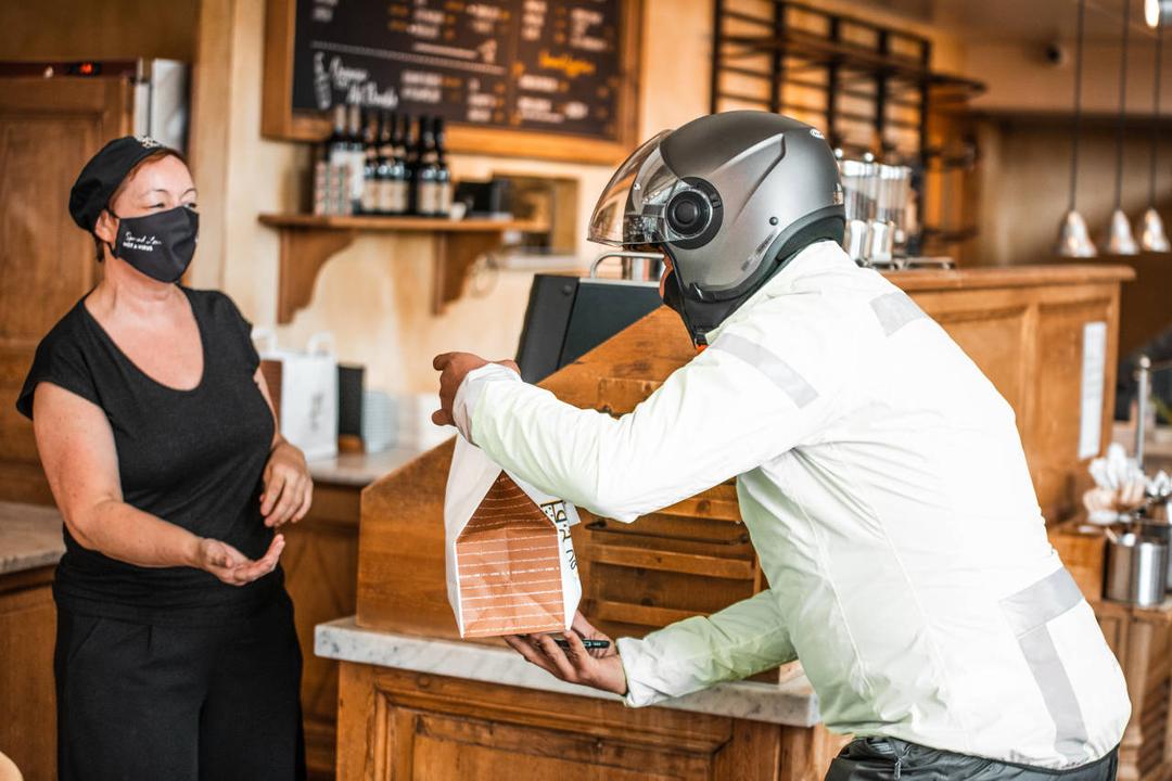 A food delivery driver receives food from the restaurant staff.