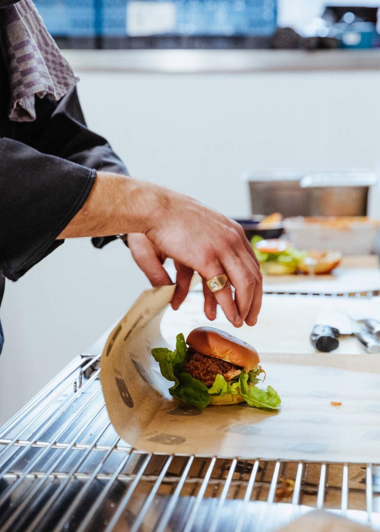A chef preparing a burger to be delivered to a customer.